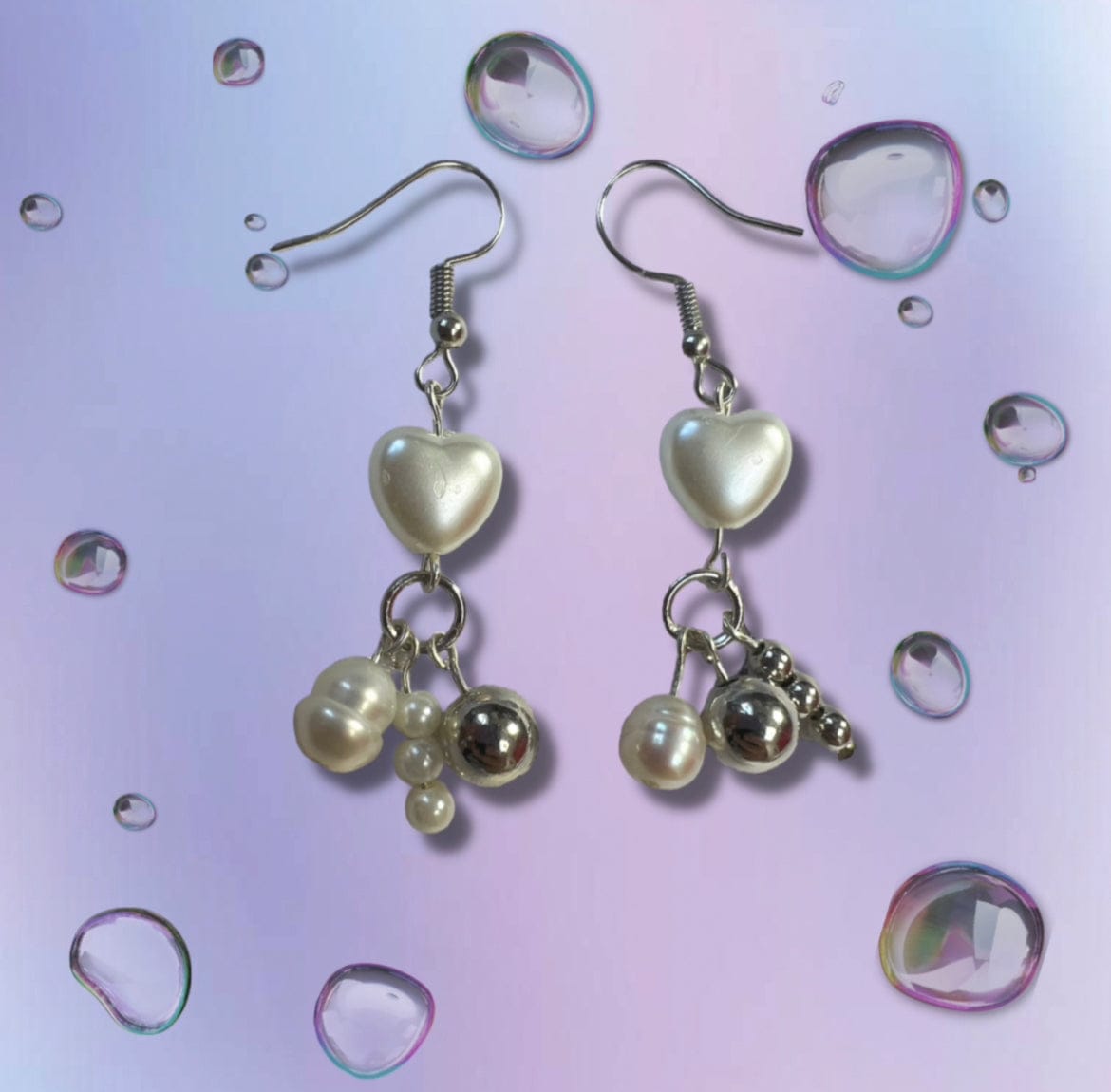 These earrings are embellished with pearl bubble hearts. Attached to the heart there is a steel ring. Dangling from the ring  are pearls, silver beads, and pearl beads.